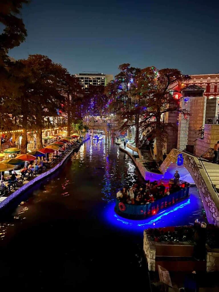 san antonio River Walk by Night with boat passin through twinking christmas lights