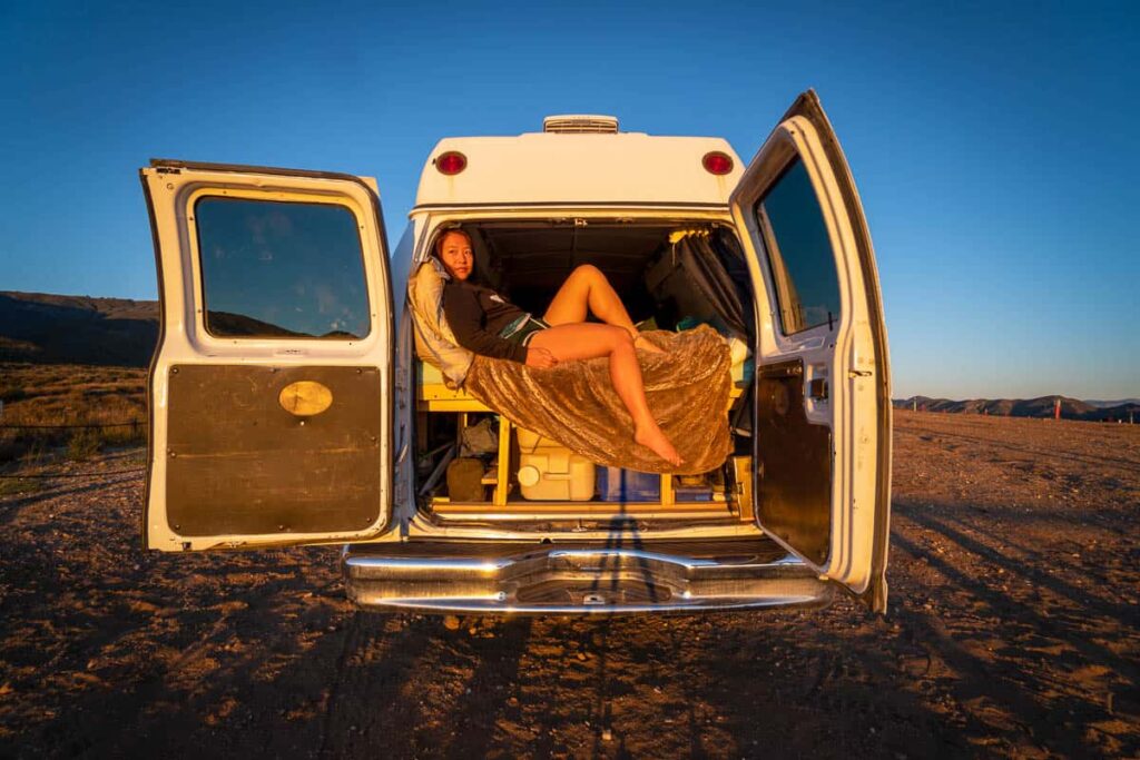 day trip nomad siting on back of vanlife in the desert