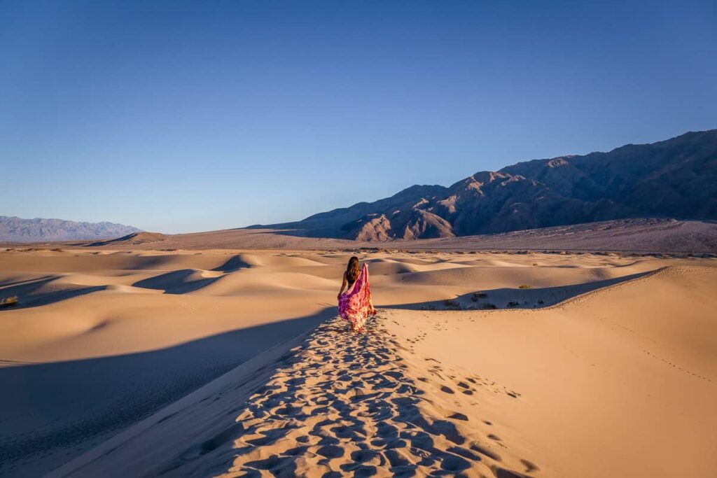 cat xu posing in the mesquite sand dunes with a red scarf in fall a best time to visit death valley national park