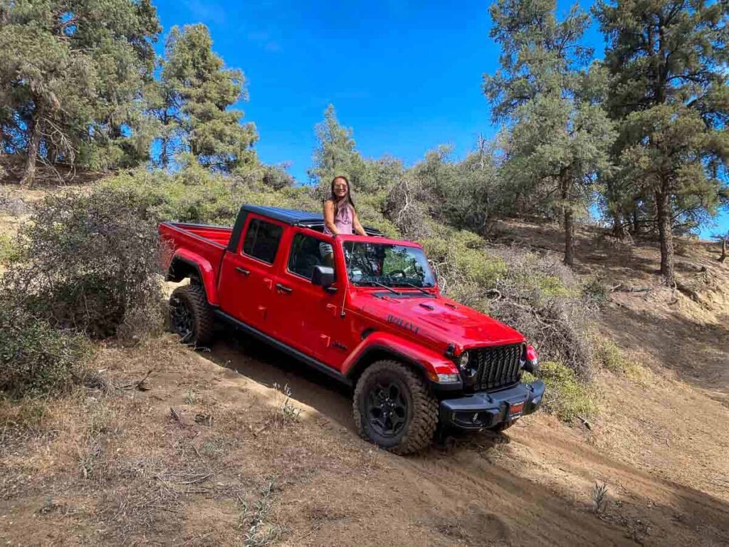 Cat Xu happily standing up in a red jeep on off road trail