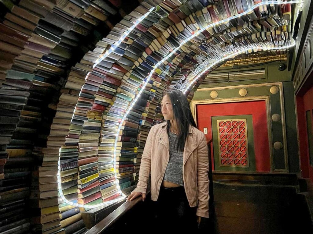Day Trip Nomad standing under the tunnel of books in the last bookstore