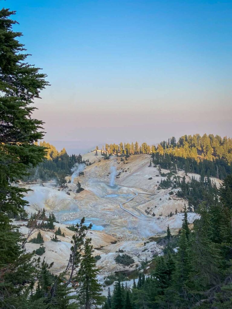 panoramic shot of bumpass hell as the sun is setting with steam coming out