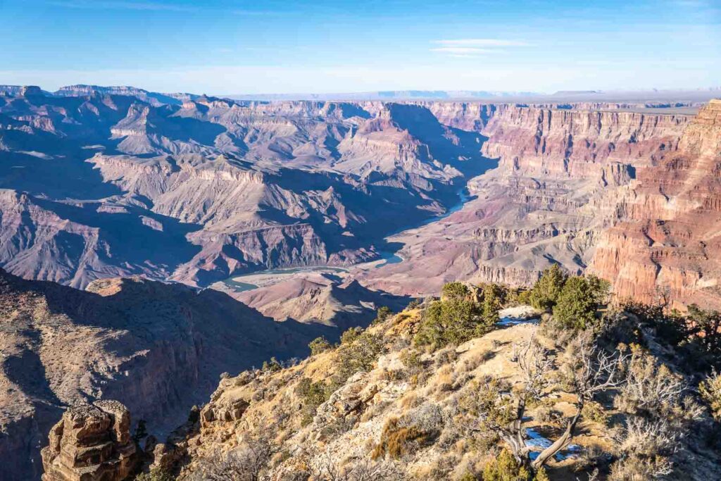 a shrubby hill in front of a grand canyon south rim viewpoint