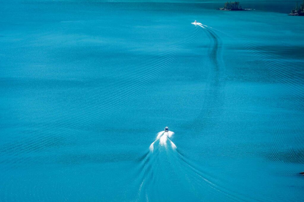 a boat gliding across the blue waters of the lakes in north cascades national park