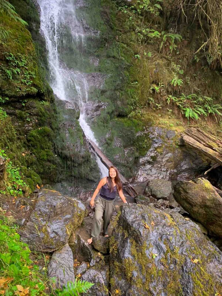 day trip nomad standing in front of a waterfall on a one day in olympic national park itinerary