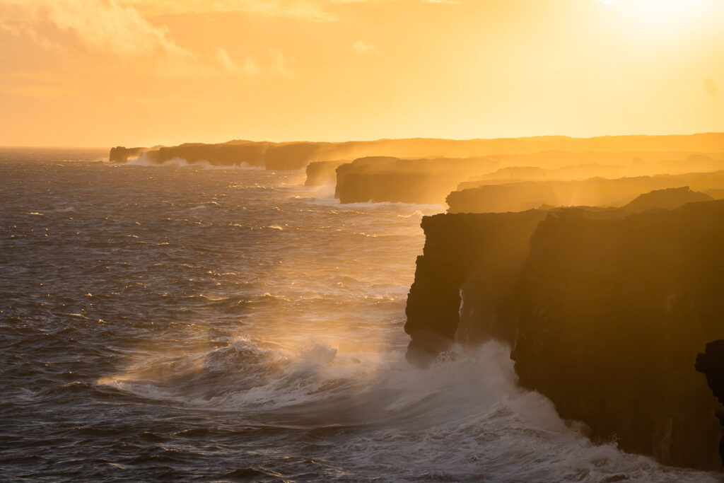 Hōlei Sea Arch at sunset with the layered mountains and the waves crashing
