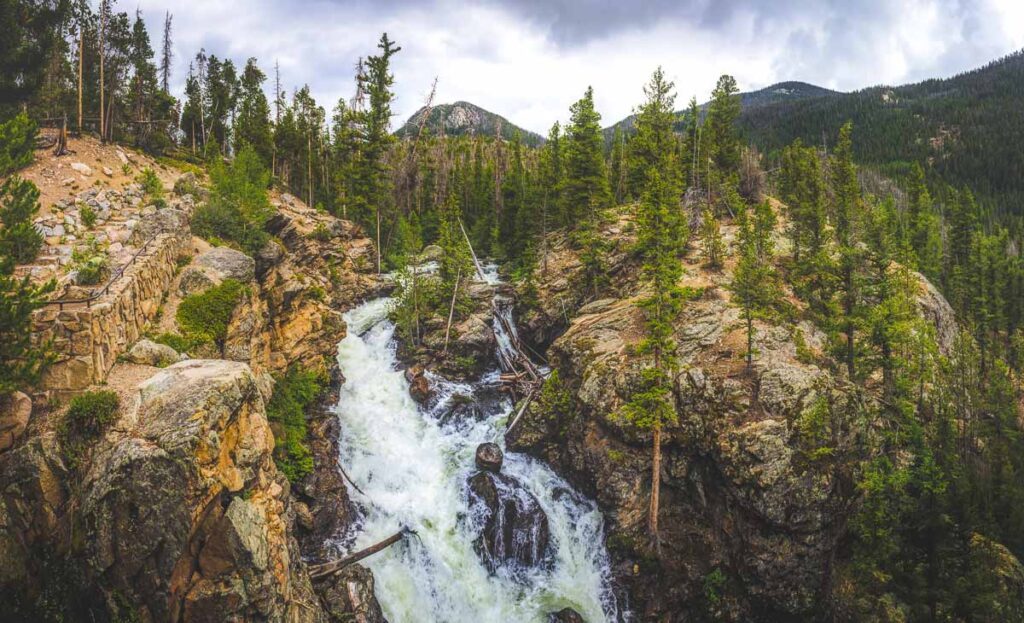 Adams Falls on a cloudy day with mountains and trees in the background along the East Inlet Trail of Rocky Mountain National Park, Colorado