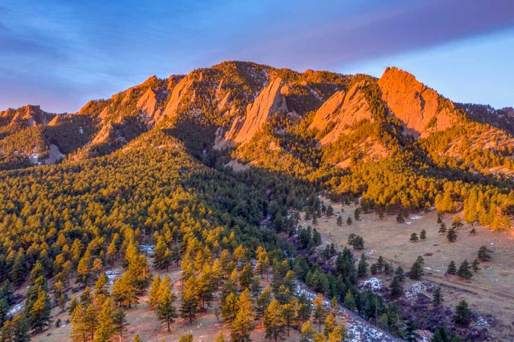 Aerial photo just after sunrise on Green Mountain with the Flatirons illuminated above Boulder, Colorado in winter.