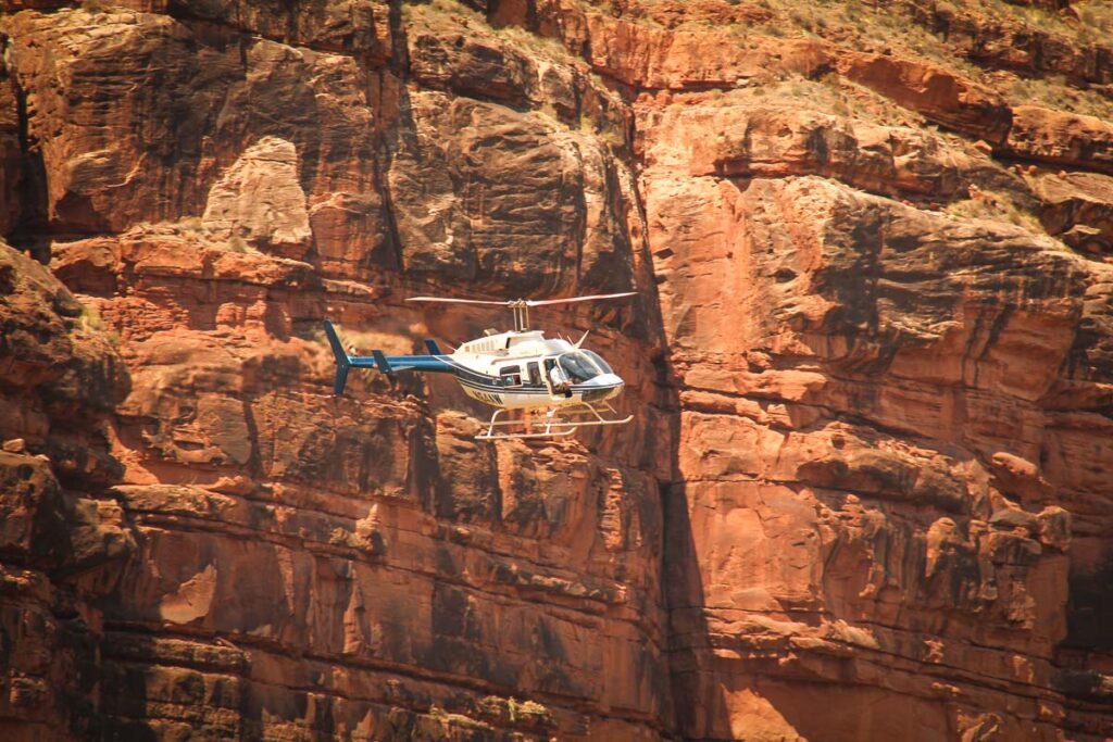 Helicopter in front of large red canyon wall