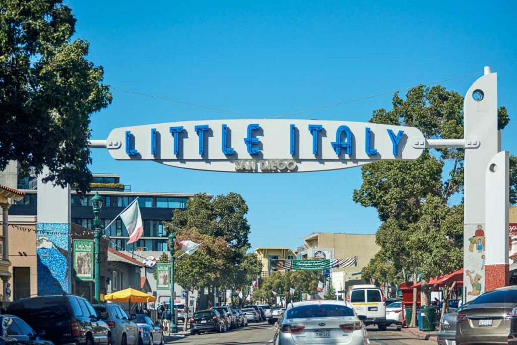 Little Italy neighborhood vintage style entrance sign. Cars riding on road