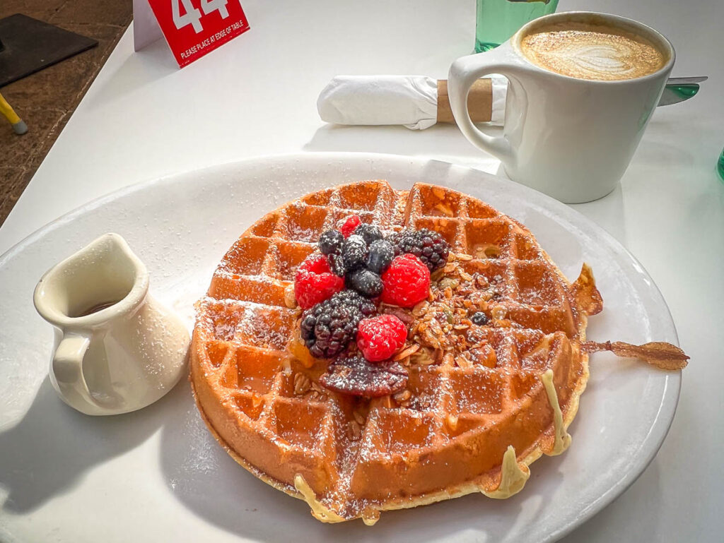 delicious waffle sitting on a plate next to coffee in Sunflower Caffe