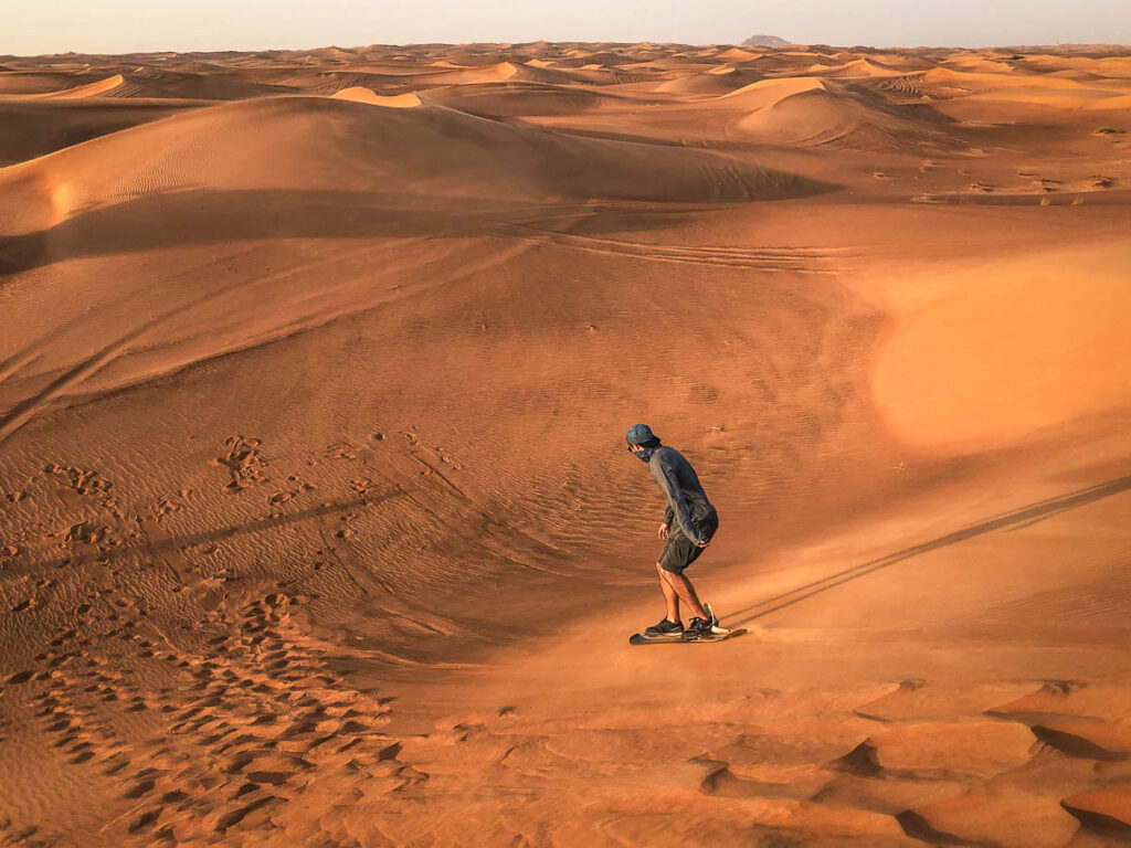 Man sandboaring on the dunes of a desert