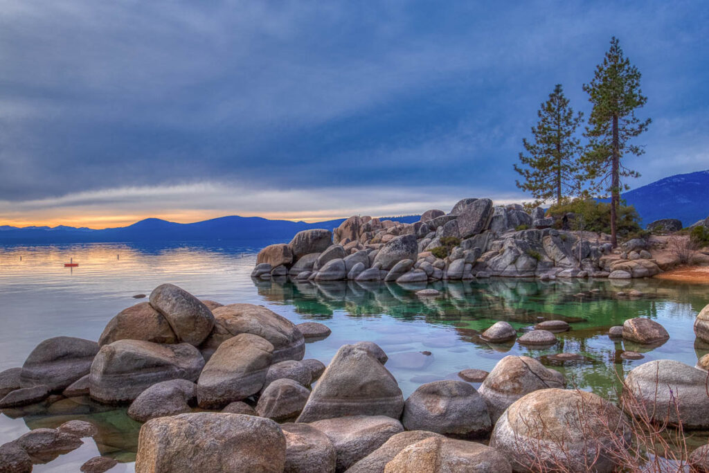 Colorful sky at sunset at Sand Harbor with calm water, beautiful rock formations, and mountains in the background, Lake Tahoe, Carson City, Nevada