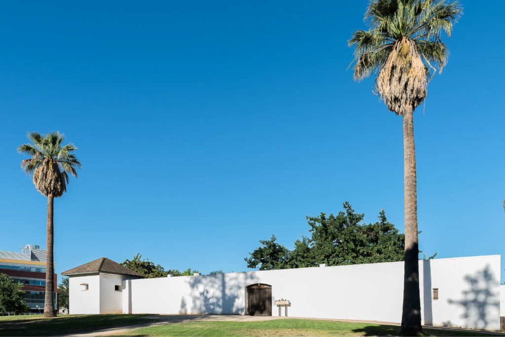 The white Sutter's Fort contrasted against the sunny sky with two palm trees