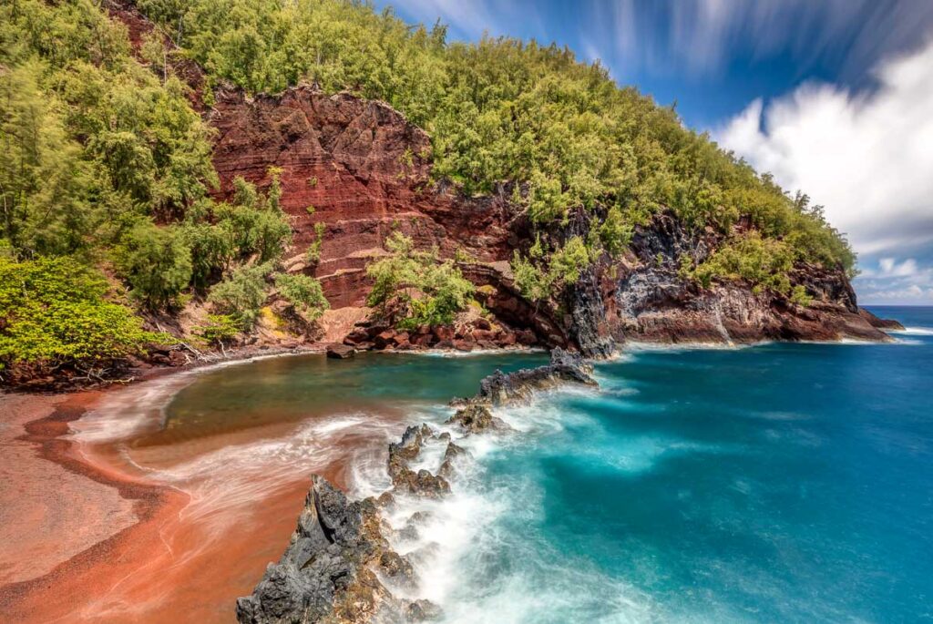 Maui's red sand beach meets turquoise ocean water