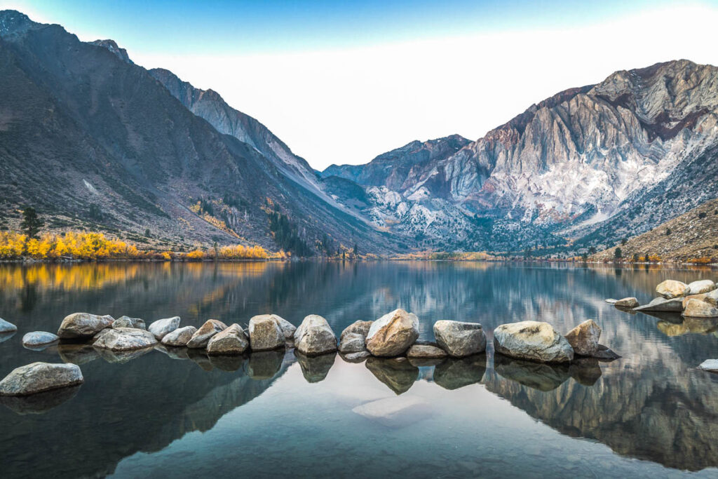 Long exposure sunrise photo of Convict Lake, an alpine lake in the Sierra nevada mountains of California, with alpenglow on the mountain peak on a fall morning