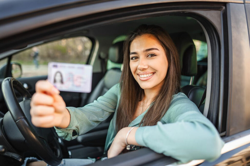 Girl holding a US drivers license inside a car