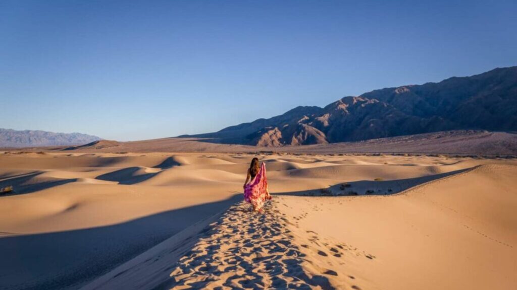 cat xu posing in the mesquite sand dunes in death valley national park with a red scarf