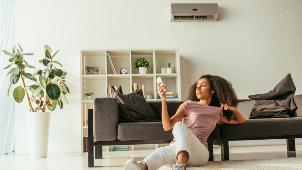 woman sitting on the floor while turning on the ac