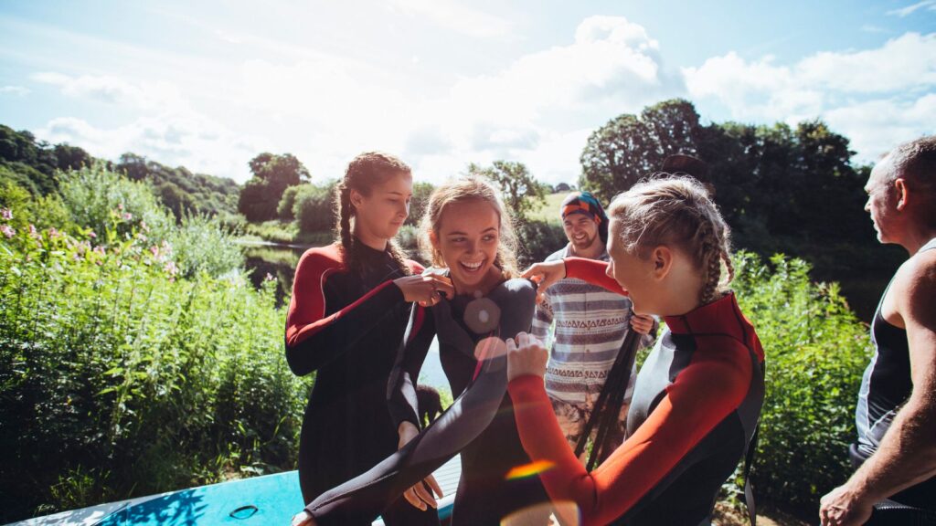 girl helping a friend put her wetsuit on