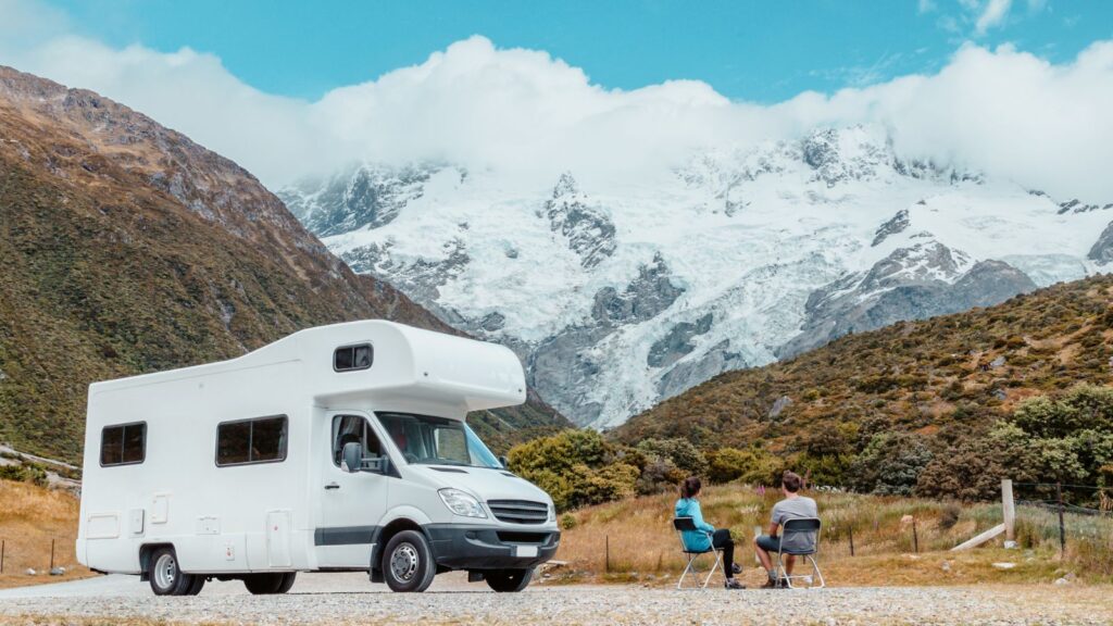 Couple sitting with RV road trip with mountains,