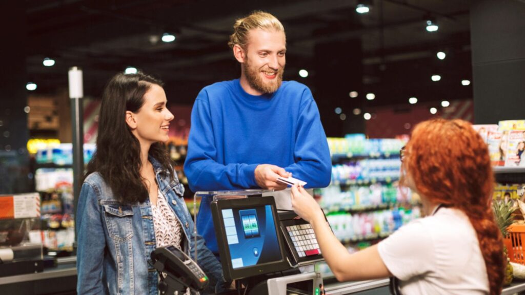 young cheerful couple paying at the cashier using credit card