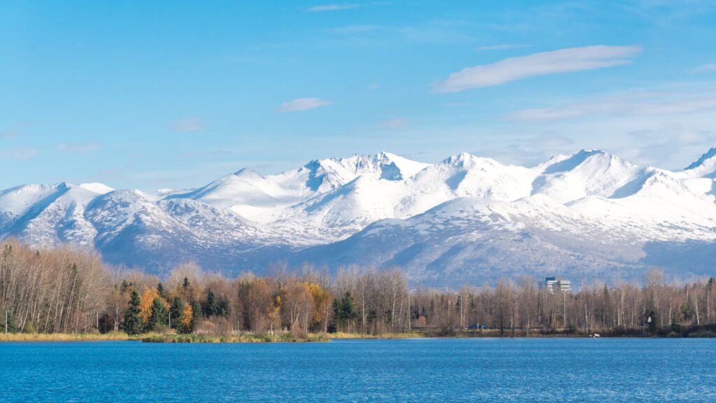 Snow cap Chugach Mountains and Downtown Anchorage buildings from Westchester Lagoon park