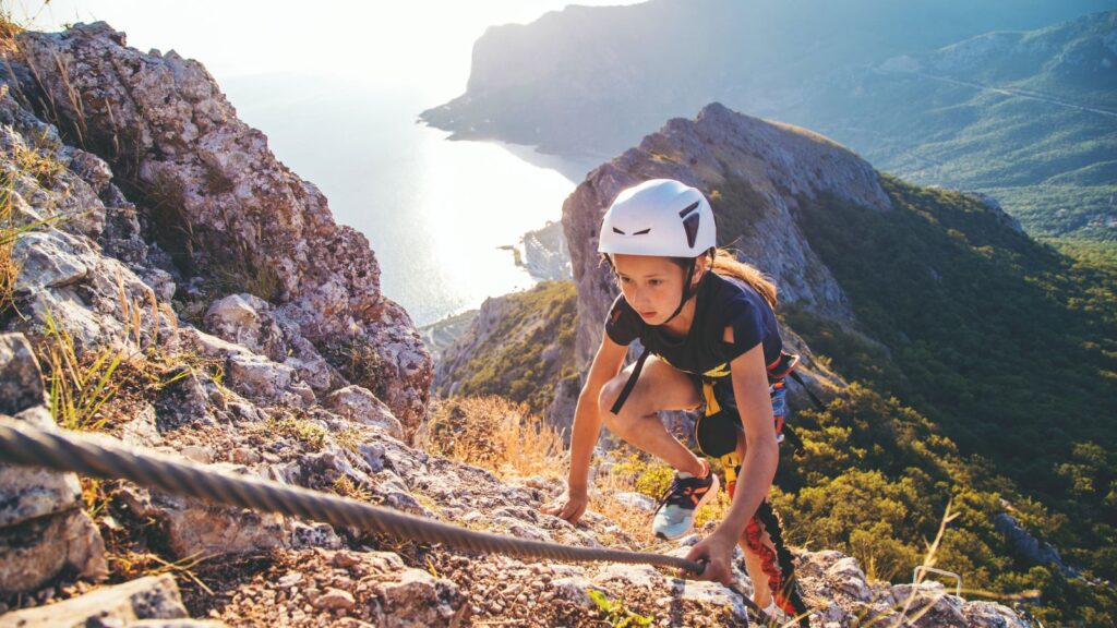 Kid girl climbing mountain