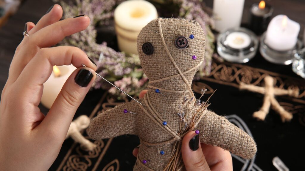 Woman Stabbing Voodoo Doll with Needle at Table, Closeup. Curse Ceremony