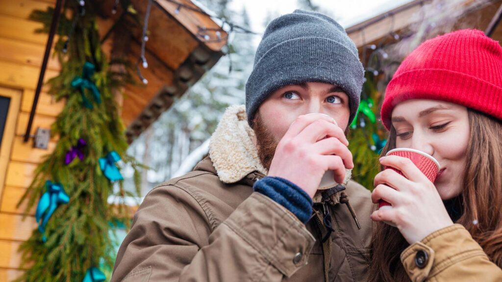 Man and woman drinking hot coffee on christmas market