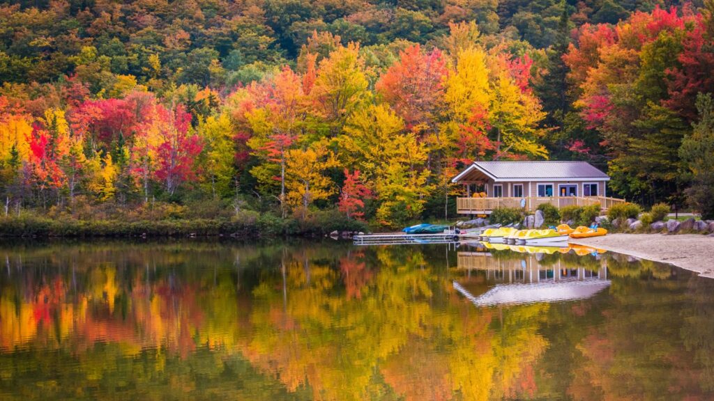 New Hampshire, Boathouse and fall colors reflecting in Echo Lake, in Franconia