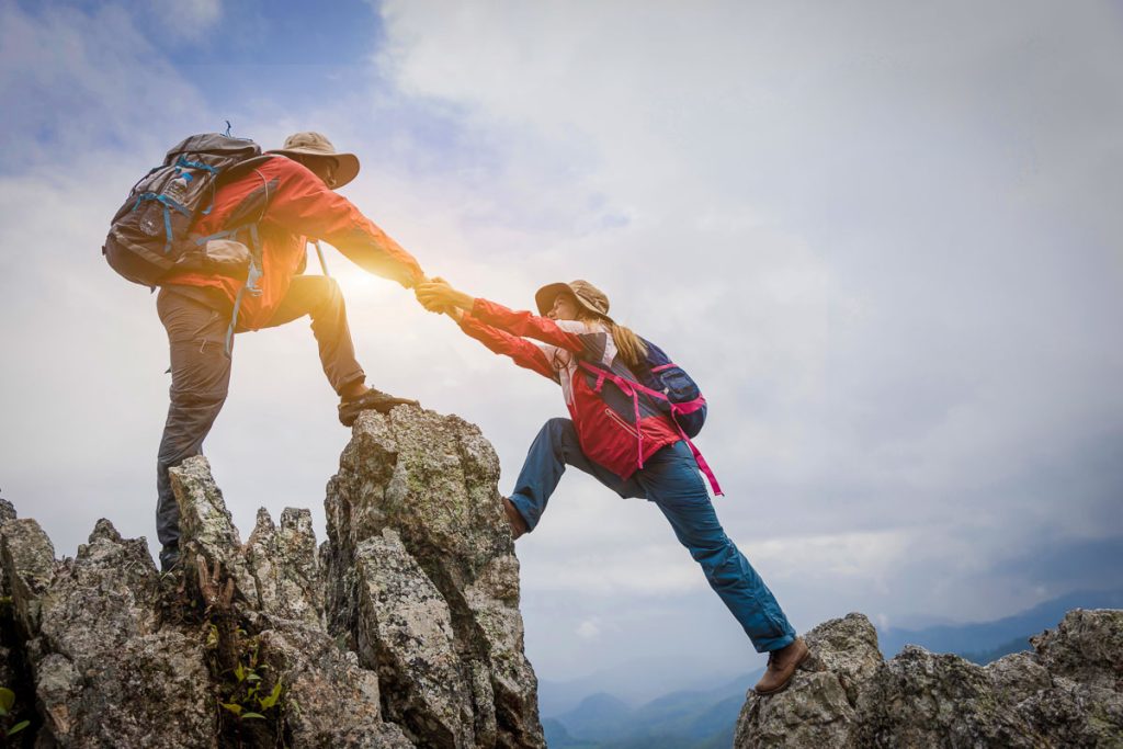 Young couple traveling, Helping hand, hiker woman getting help on hike smiling happy overcoming obstacle, Tourist backpackers walking in forest.