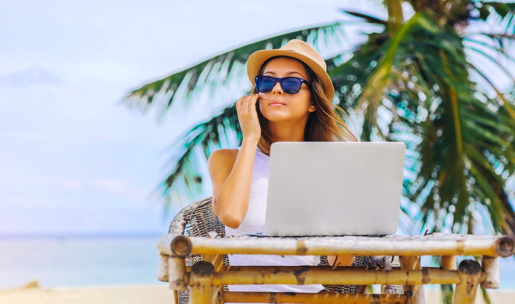 Ditigal nomad, Young woman working in laptop on the beach