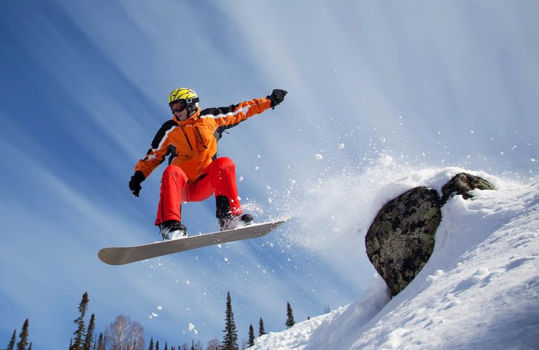 Snowboarder jumping through air with blue sky ski