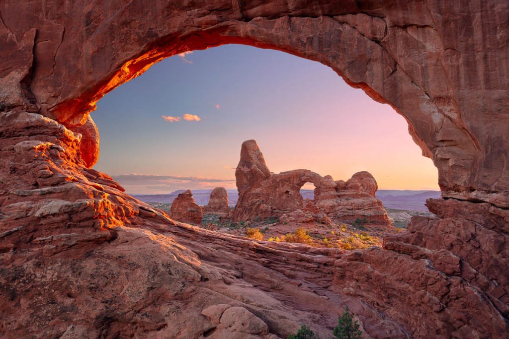 Utah, Arches National Park viewed through giant sandstone arch at sunset