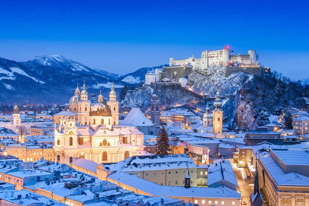 Austria, Salzburg, historic alpine city in winter twilight with snow-covered rooftops