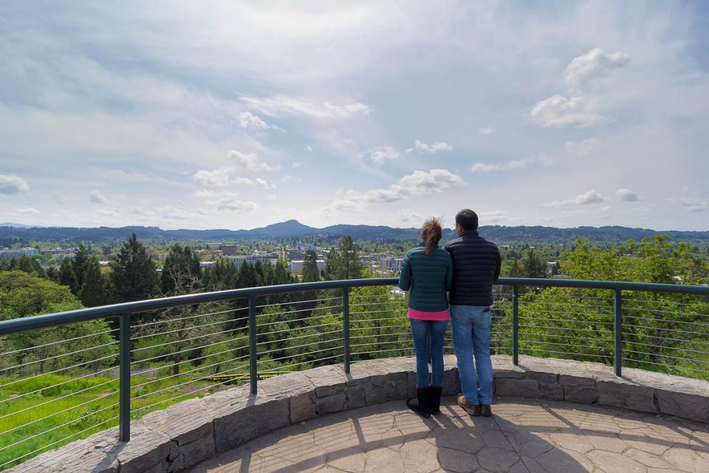 Couple at top of Skinner Butte Park viewing deck enjoying view of downtown Eugene Oregon on a beautiful day