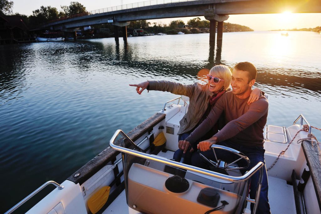couple enjoying a relaxed ride on a small motorboat beneath a concrete bridge