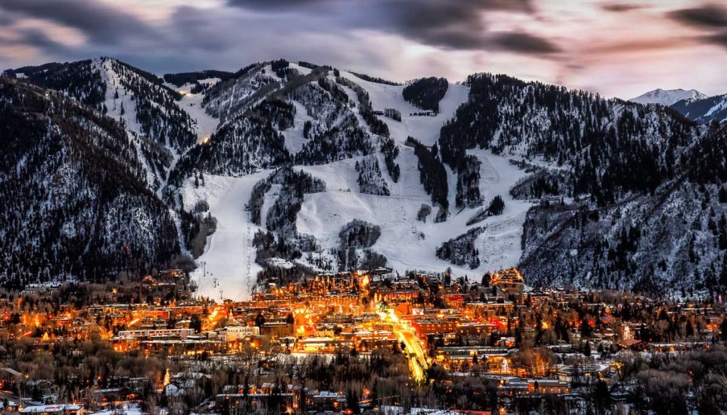 Aspen, Colorado, USA, mountain town illuminated at night beneath snow covered Rocky Mountains and ski slopes