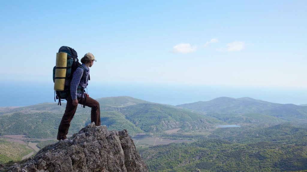 Backpacker girl standing on a high rock