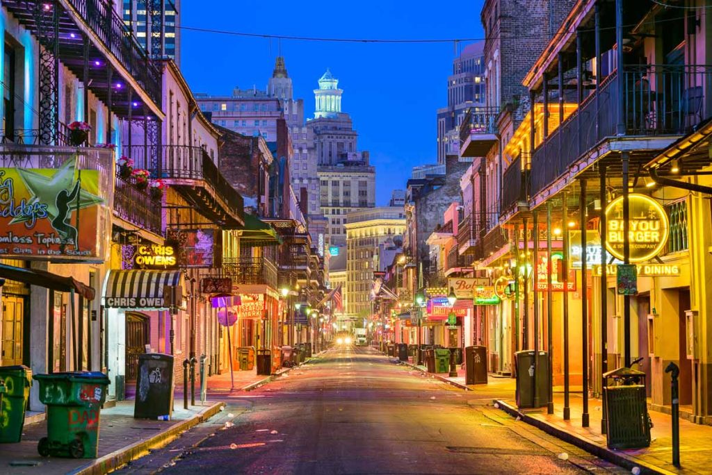 Bourbon Street in New Orleans glowing at night with neon lights and historic balconies