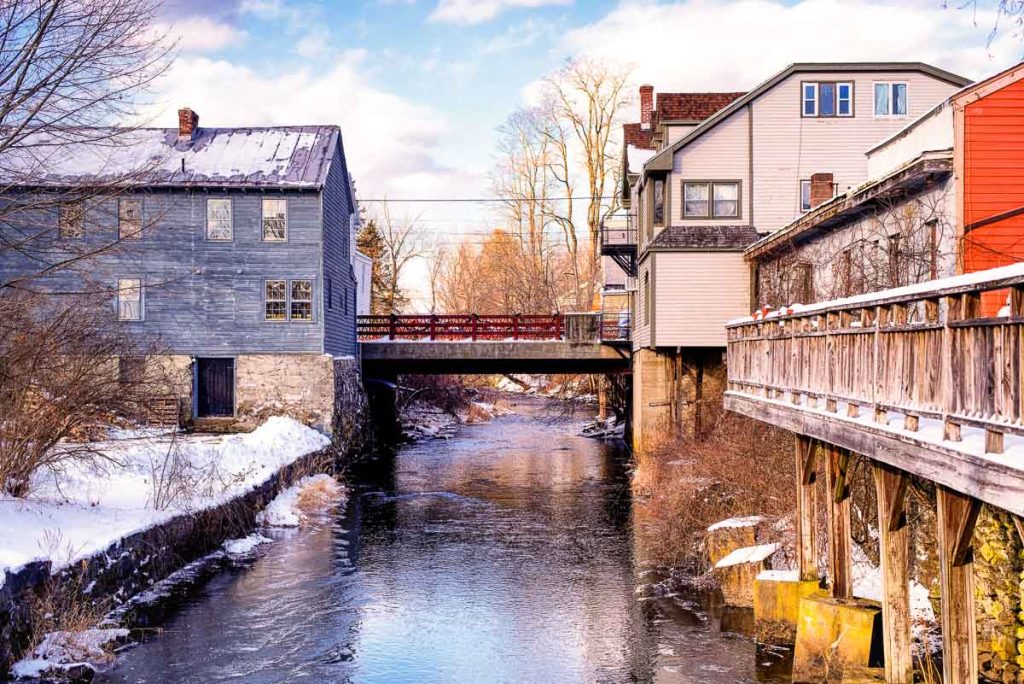 Old buildings lining the williams river running through the village of west stockbridge massachusetts on a sunny winter day.