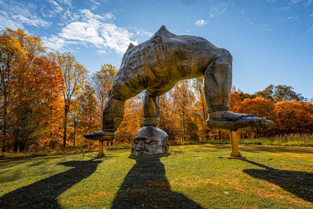 Zhang Huan's "Three Legged Buddha" is a monumental copper and steel sculpture at Storm King Art Center, with an inverted figure and three massive legs on the ground